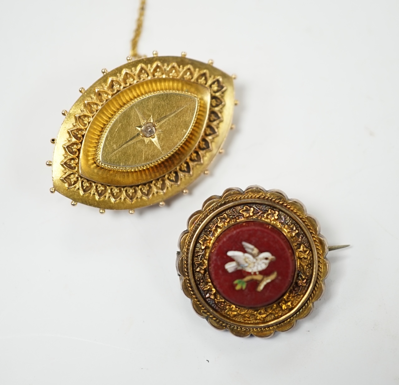 A Victorian yellow metal and diamond chip set navette shaped brooch, 39mm and a gilt metal and micro mosaic set circular brooch. Fair condition.